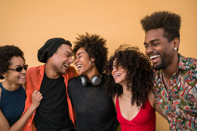 Cheerful friends standing against colored background