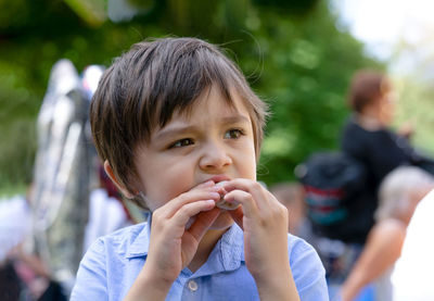 Cute boy looking away while eating food outdoors