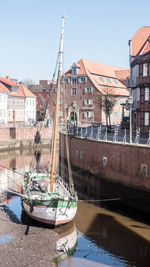 Boats moored in river by buildings in city