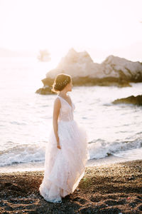 Woman standing at beach against sky