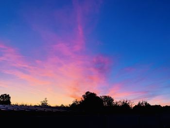 Silhouette trees against dramatic sky during sunset