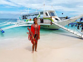 Portrait of young woman standing on shore at beach against sky