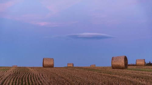 Hay bales on field against sky