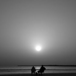 Silhouette people on beach against clear sky during sunset