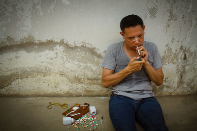 Mature man sitting by narcotics against wall