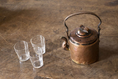 High angle view of antique tea kettle and glasses on floor at home