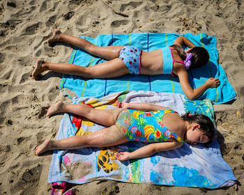 Full length of girls sitting on sand at beach