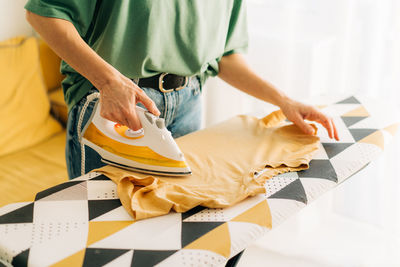 Close-up of an unrecognizable woman ironing linen on an ironing board.