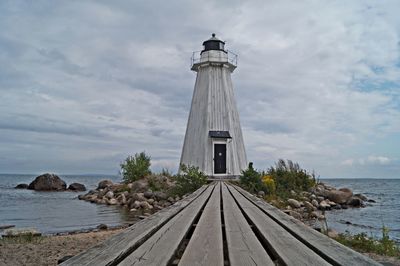 Lighthouse by sea against sky