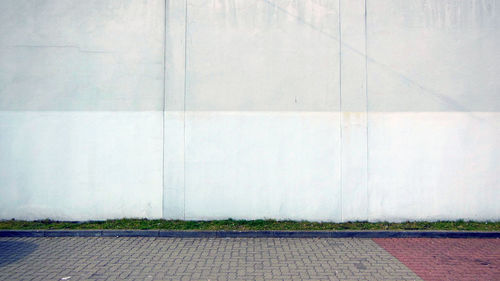 Paved walkway against white wall