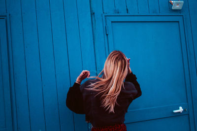 Rear view of woman standing against blue wall