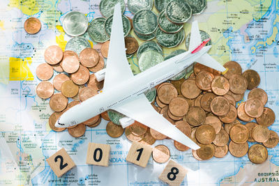 Close-up high angle view of coins and model airplane on map