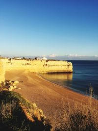 Scenic view of beach against clear blue sky