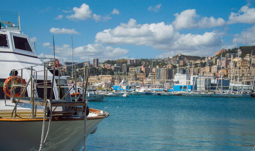 Boats moored at harbor against sky in city