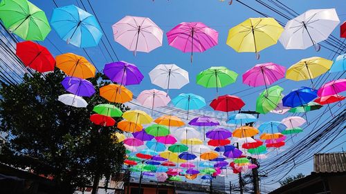 Low angle view of multi colored umbrellas hanging against sky