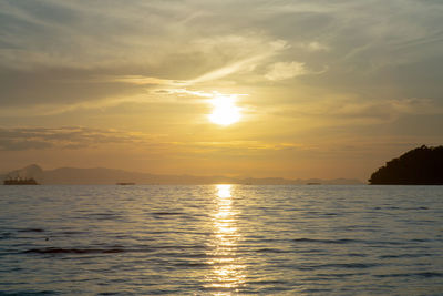 Landscape of sea with silhouette of island and orange light of sunrise