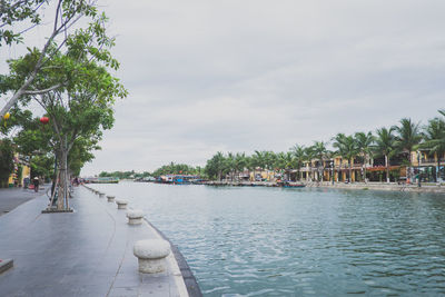 Scenic view of canal in city against cloudy sky