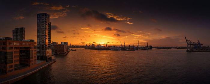 Panoramic view of sea and buildings against sky during sunset