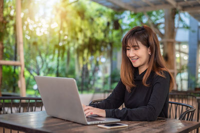 Young woman using phone while sitting on table