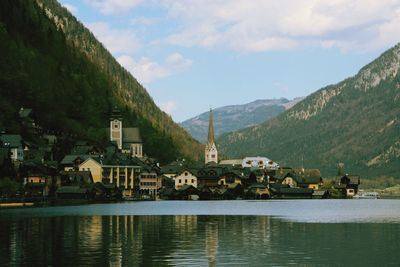 Houses by lake and buildings against sky