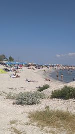 People on beach against clear sky