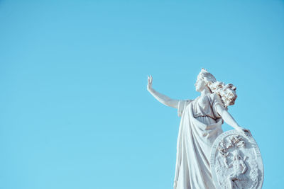 Low angle view of angel statue against clear blue sky