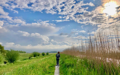 Rear view of man standing on field against sky