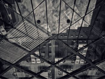 Tables an chairs in cafe seen through glass ceiling with reflection of building and sky