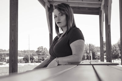 Side view of woman sitting against clear sky