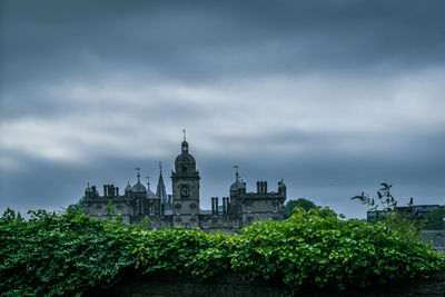 View of trees and buildings against cloudy sky