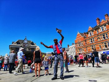 People at town square against clear blue sky