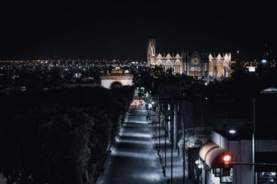 High angle view of illuminated street amidst buildings in city at night