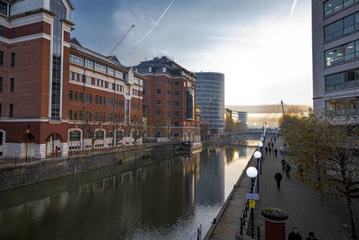 Bridge over river by buildings in city against sky