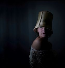 Portrait of woman wearing headwear against black background