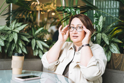 Adult brunette middle aged woman plus size body positive in casual clothes with coffee in cafe