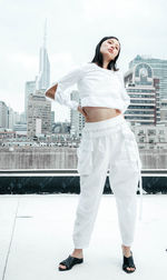 Portrait of young woman standing against buildings in city