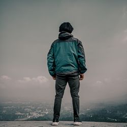 Rear view of man standing on landscape against sky