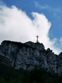 Low angle view of cross on rock against sky