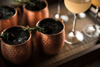Copper mugs with rosemary sprigs and wine glasses arranged for celebration and entertaining guests 