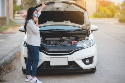 Rear view of woman standing on car in city