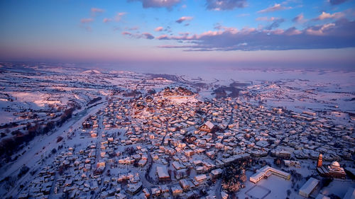 High angle view of snow covered townscape against sky during sunset