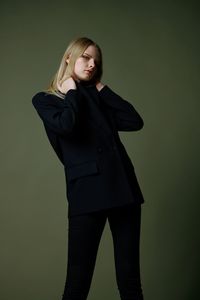 Portrait of young woman standing against blue background