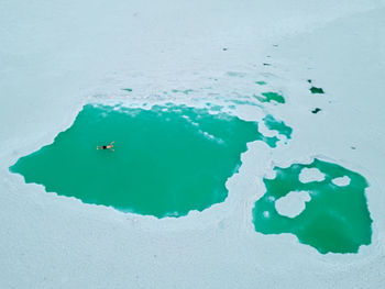 Aerial photo of man floating in emerald water in salt flats of guerrero negro baja california.