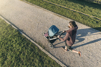 High angle view of man walking with baby stroller on road