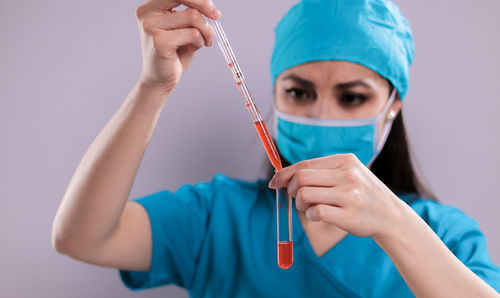 Midsection of woman holding mask against wall