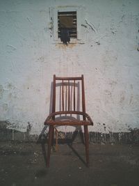 Empty chair and table against wall