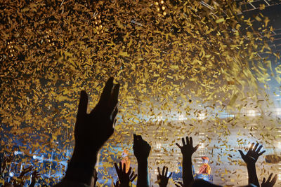 Cropped arms raised below confetti during music festival