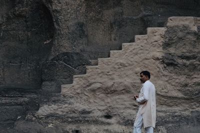 Side view of young man standing against wall