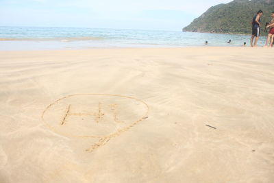 Heart shape on sand at beach against sky