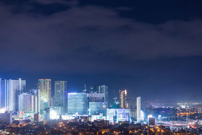 Illuminated buildings in city against sky at night